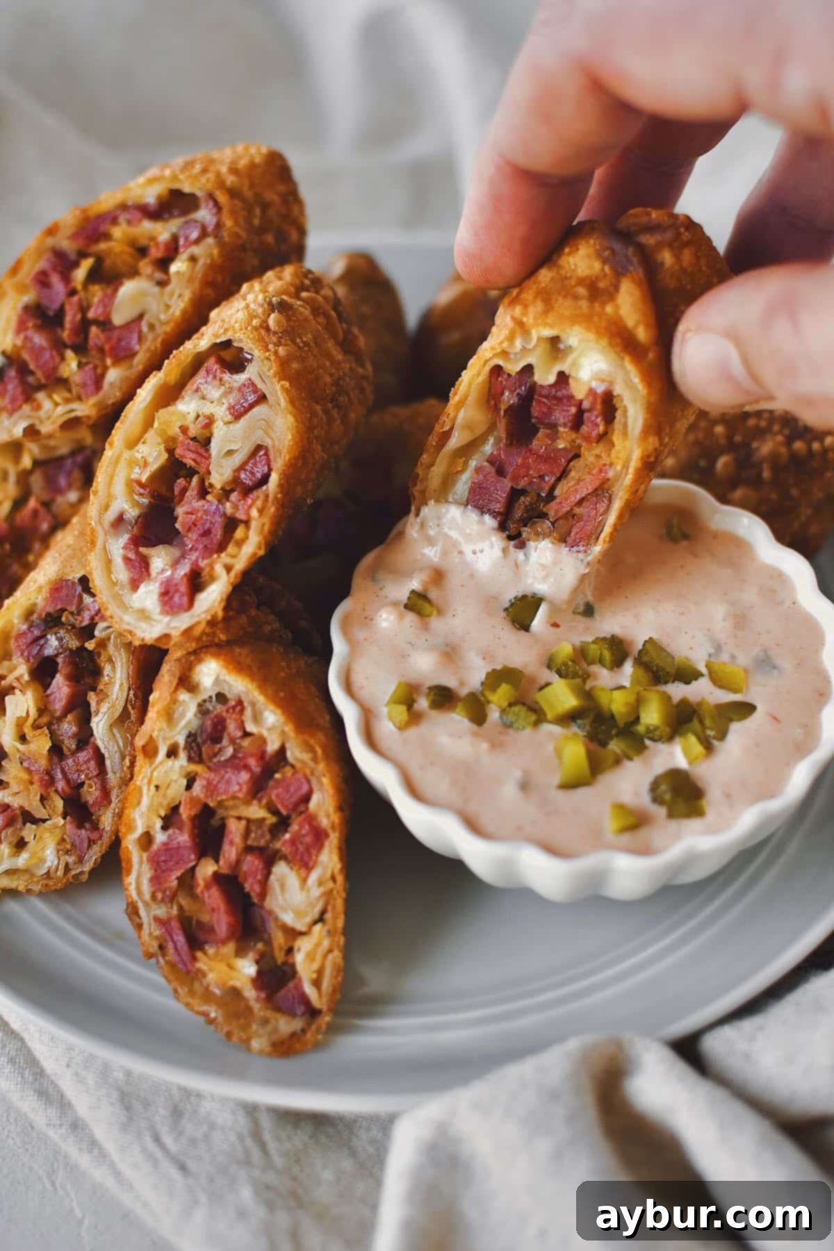Dipping half a Reuben Egg Roll in Russian dressing, ready to eat it.