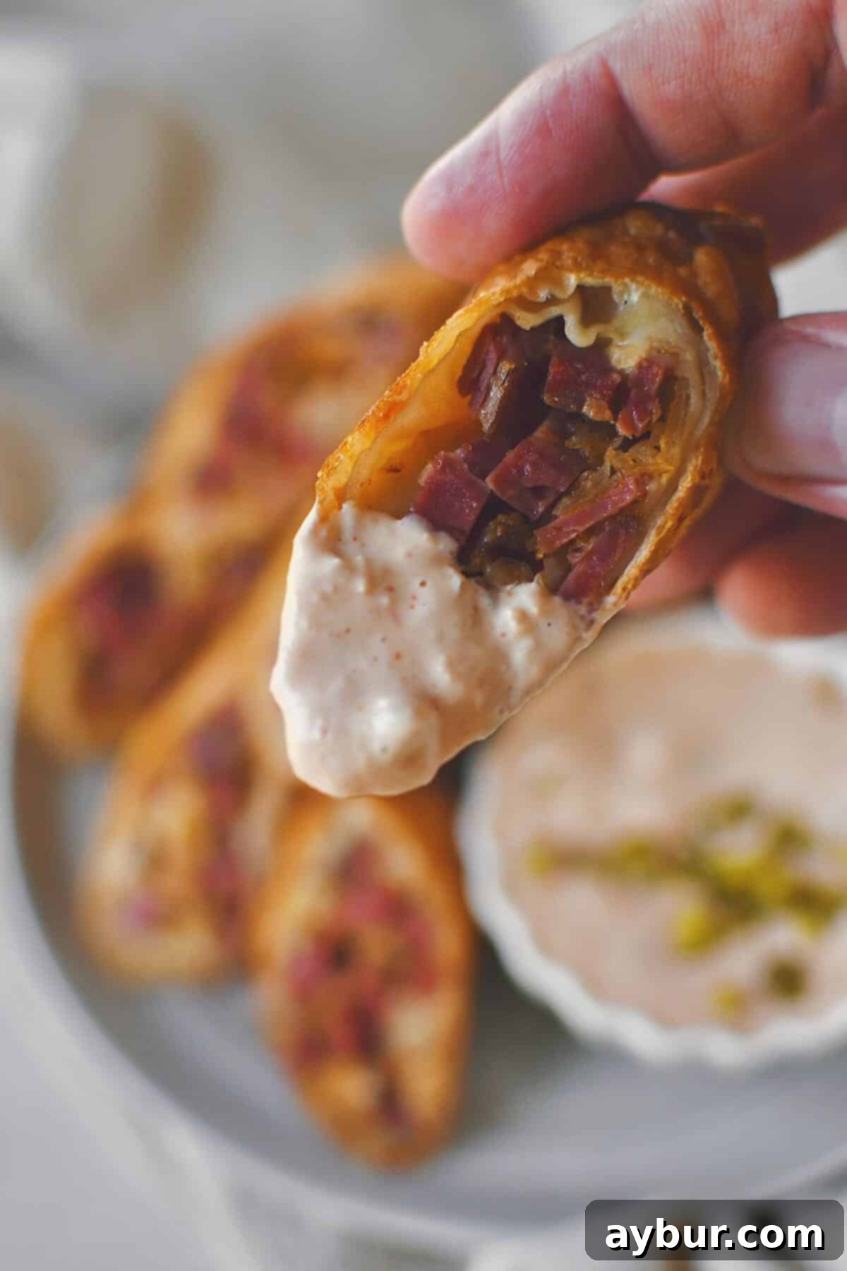 Dipping half a Reuben Egg Roll in Russian dressing, ready to eat it.