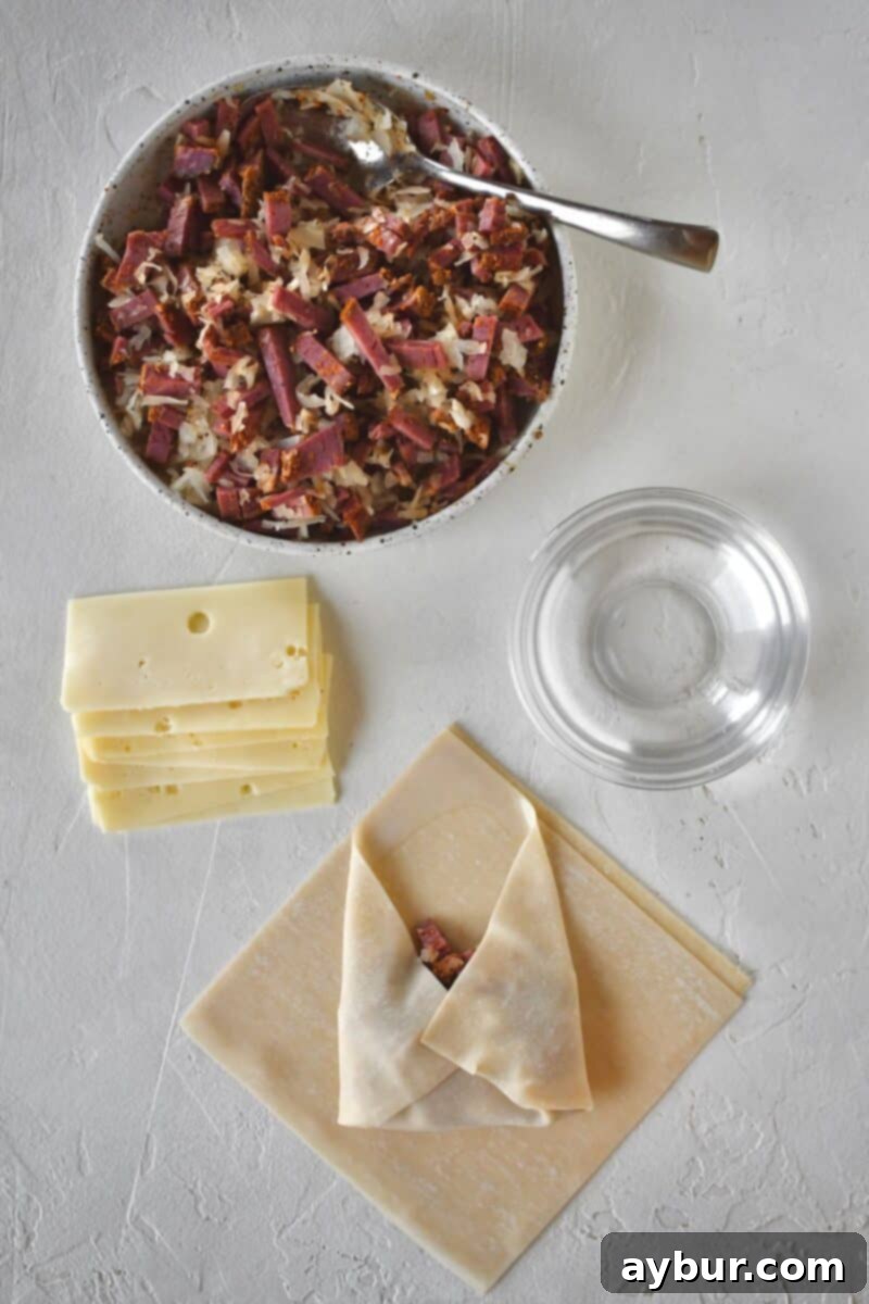 Beginning to fold an egg roll, folding up the bottom corner, and the sides before forming a cylinder.