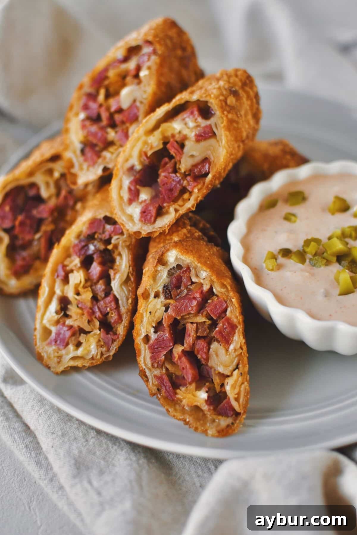 Deli-Crisp Reuben 10 Reuben Egg Rolls sliced in half on the diagonal and served on a plate with Russian Dressing.