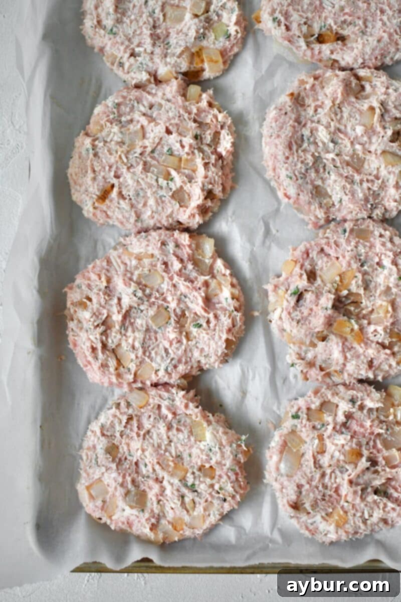 Eight perfectly formed turkey burger patties laid out on a parchment-lined tray, ready for chilling.