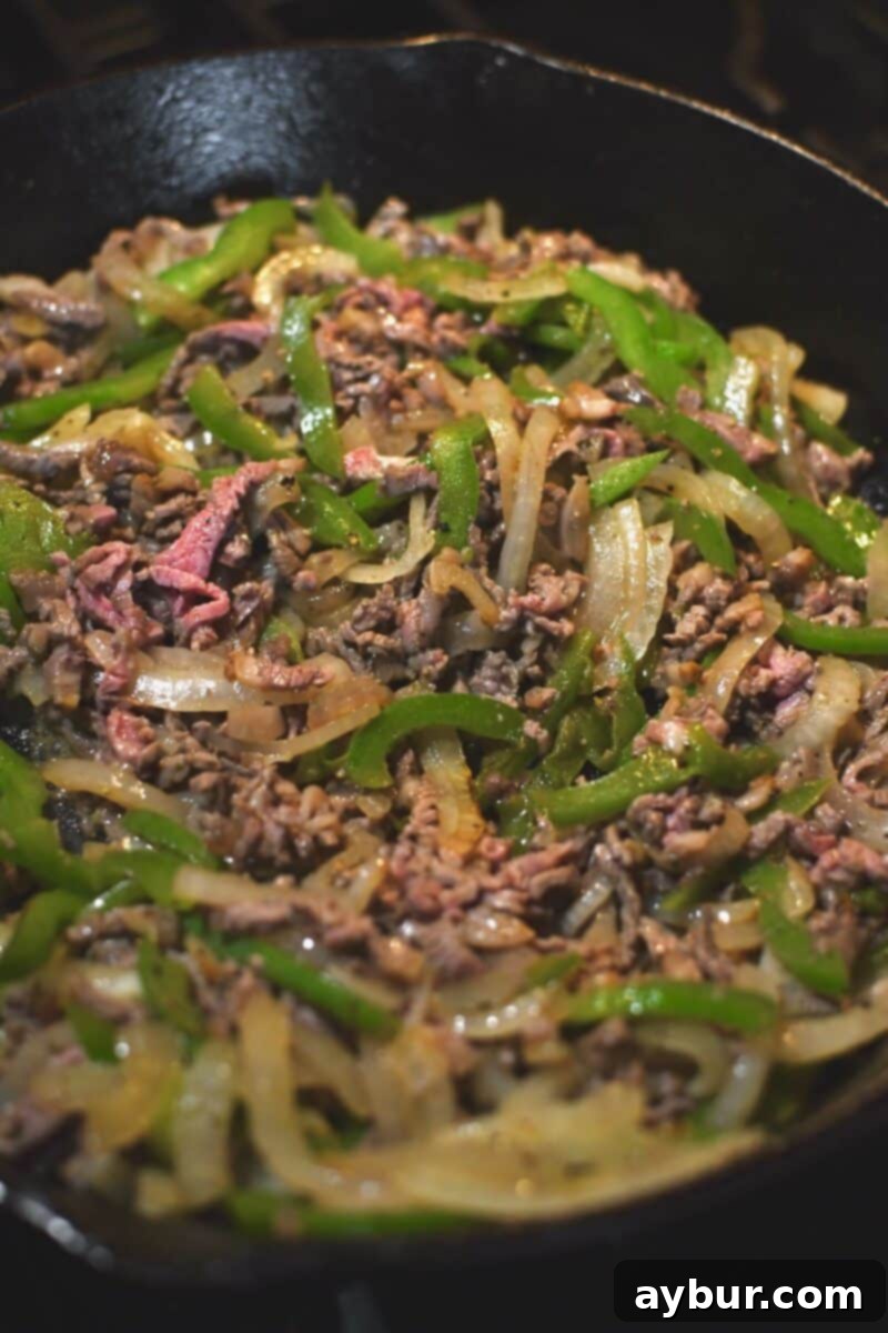 Adding the beef to the peppers and onions.