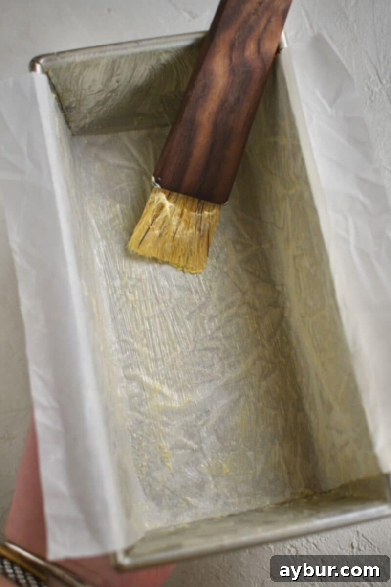 Traditional Irish Brown Bread 4 A hand is shown buttering and lining a loaf pan with parchment paper, preparing it for the bread dough.