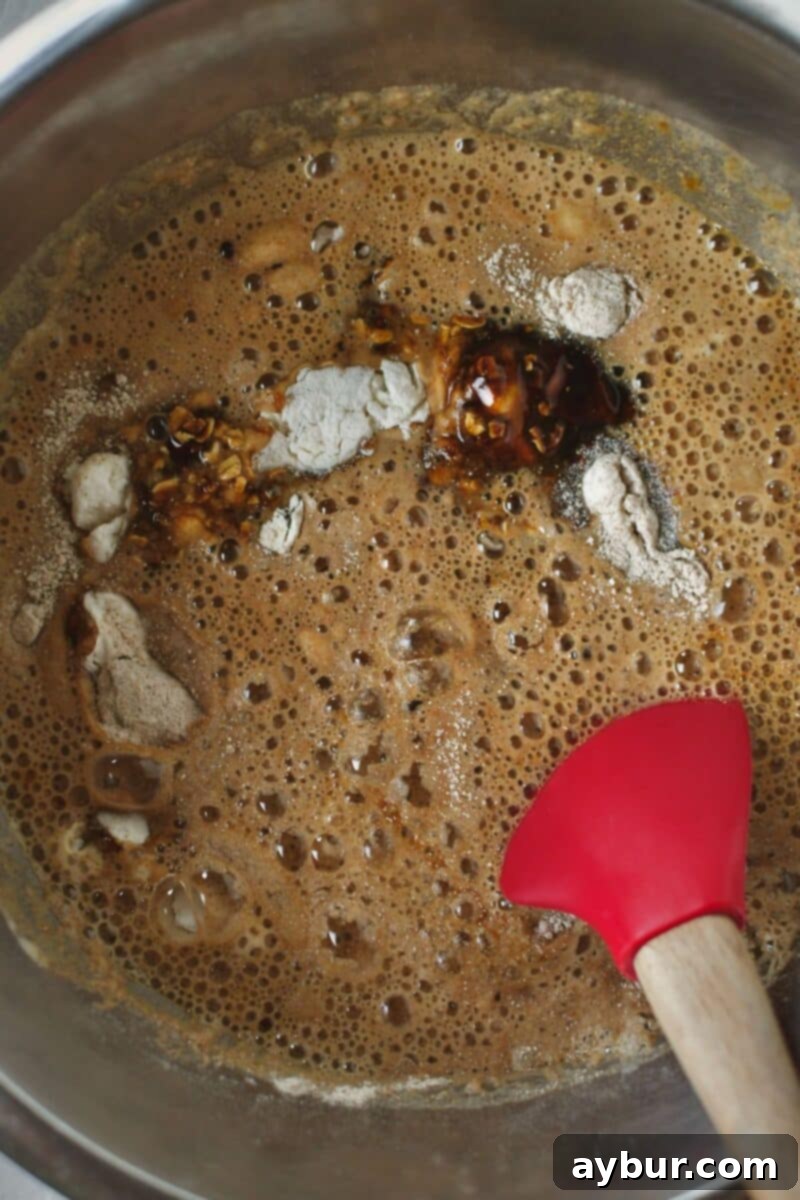 Traditional Irish Brown Bread 6 Wet ingredients, including Guinness stout, honey, and molasses, are poured into a bowl containing the dry ingredients.