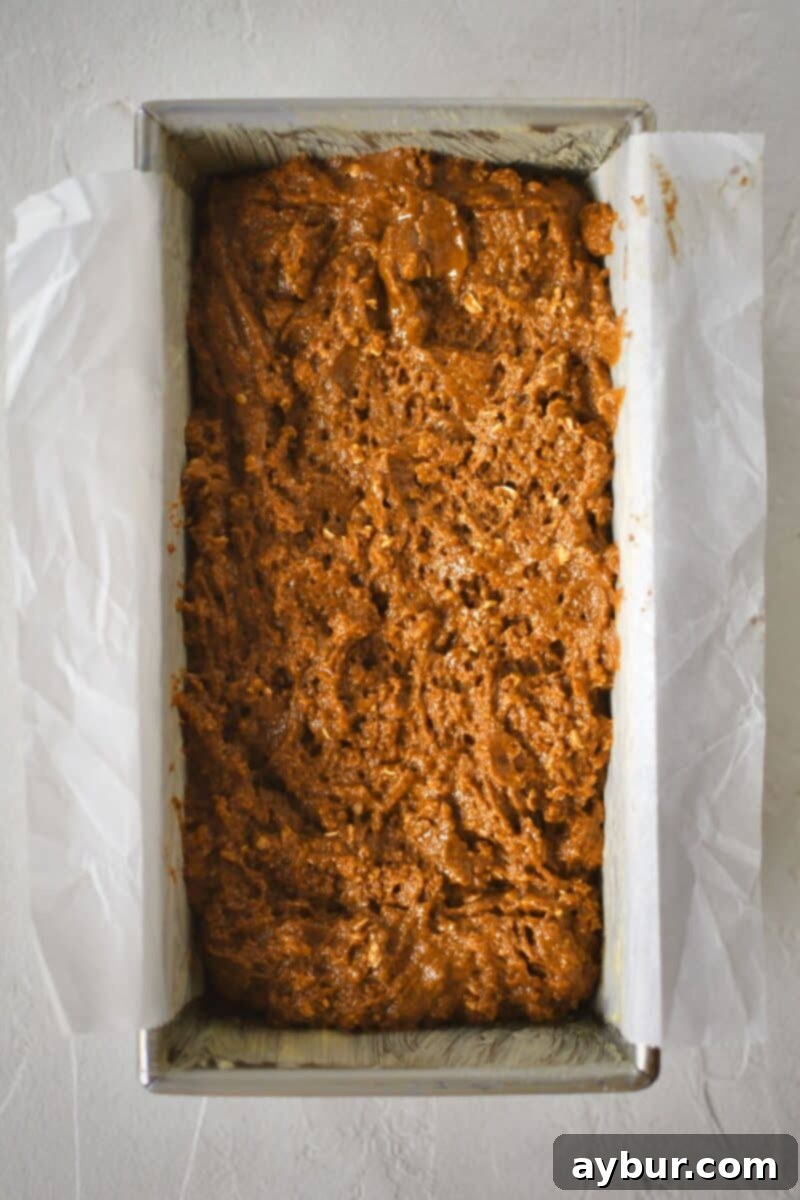 Traditional Irish Brown Bread 8 The mixed bread dough is carefully spooned and placed into a parchment-lined loaf pan, ready for baking.