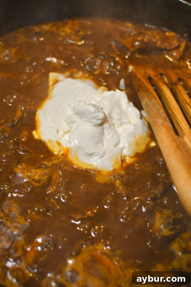 Creamy Chicken Stroganoff 11 Stirring sour cream into the thickened broth to finish the creamy stroganoff sauce.