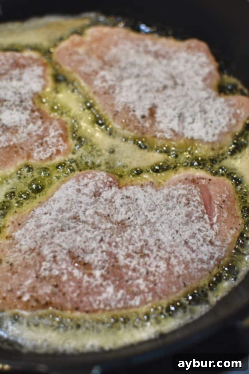 Creamy Irish Whiskey Chicken 5 Chicken cutlets searing in a skillet with butter and olive oil, developing a golden-brown crust.