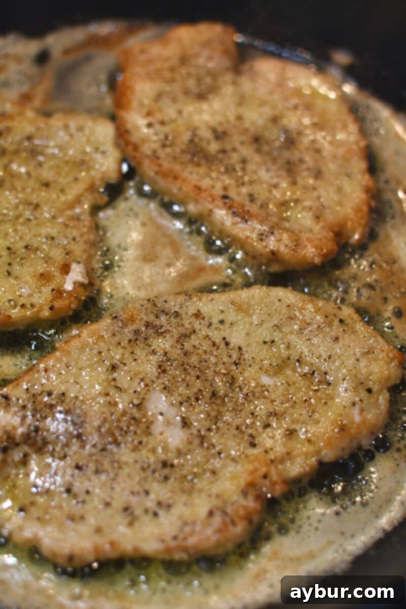 Creamy Irish Whiskey Chicken 6 Flipping the chicken cutlets during searing to achieve even browning on both sides, ensuring they're nearly cooked through.