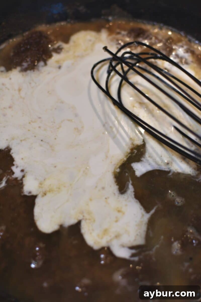 Creamy Irish Whiskey Chicken 8 Adding heavy cream and chicken stock to the roux in the pan, beginning to form the rich, smooth sauce.