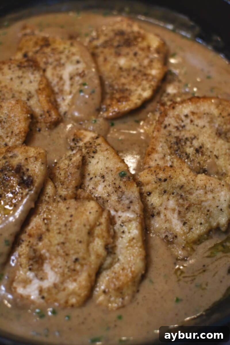Creamy Irish Whiskey Chicken 9 Returning the seared chicken cutlets to the pan to simmer and meld with the whiskey cream sauce, ensuring they cook through and absorb flavor.