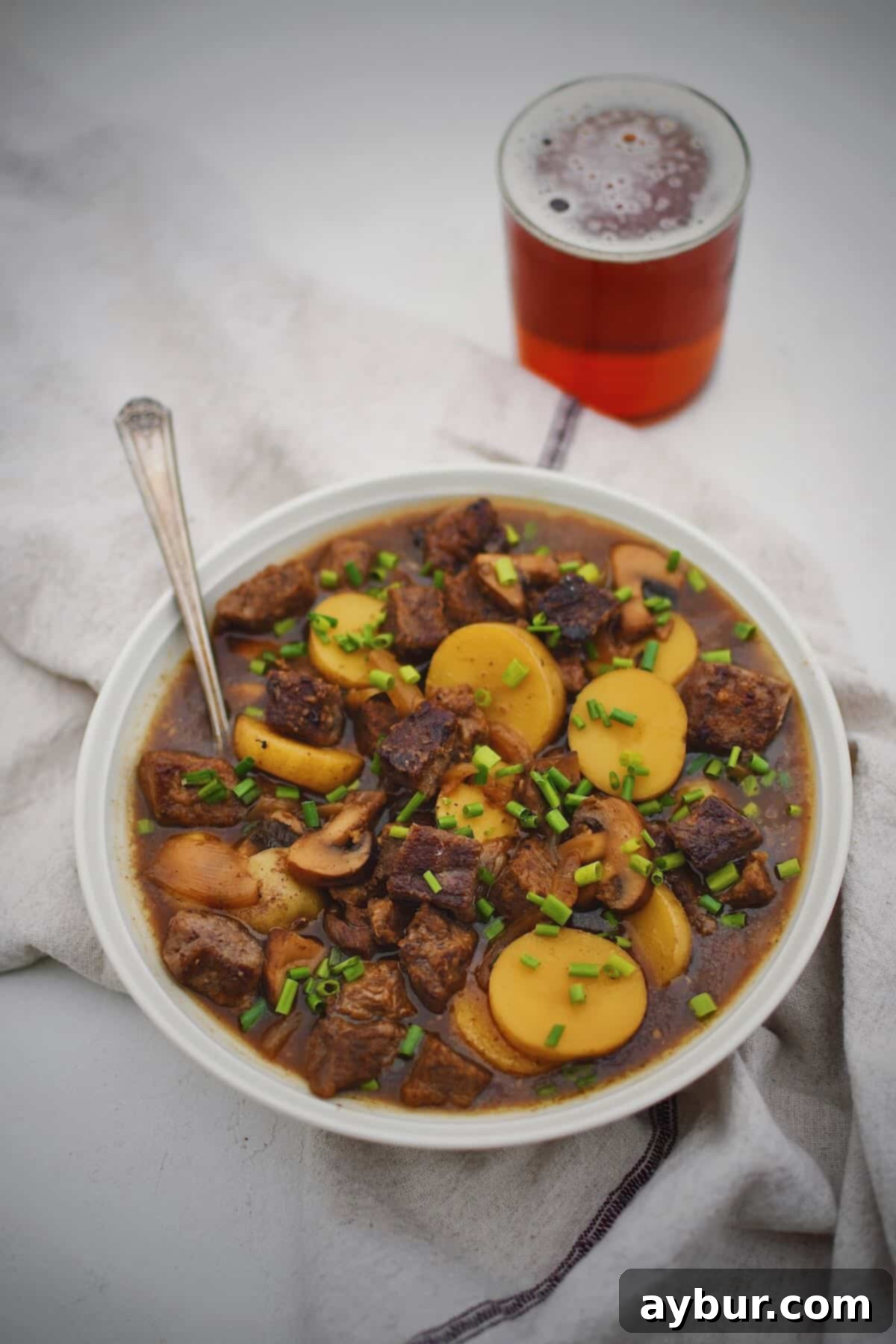 A steaming bowl of hearty Steak and Potato Soup, rich with tender beef and chunky potatoes, garnished with fresh chives, ready to be enjoyed.