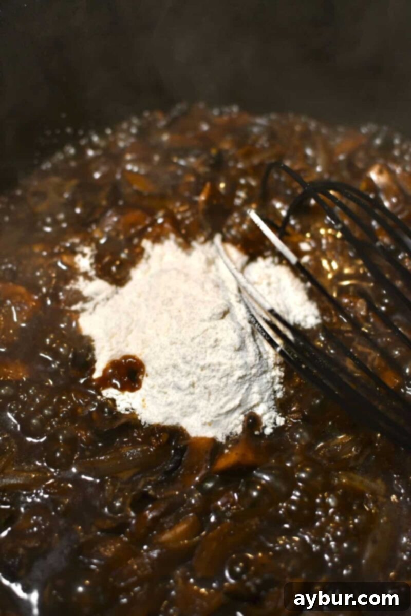 Whisking flour into the simmering beer and vegetable mixture to slightly thicken the soup base.