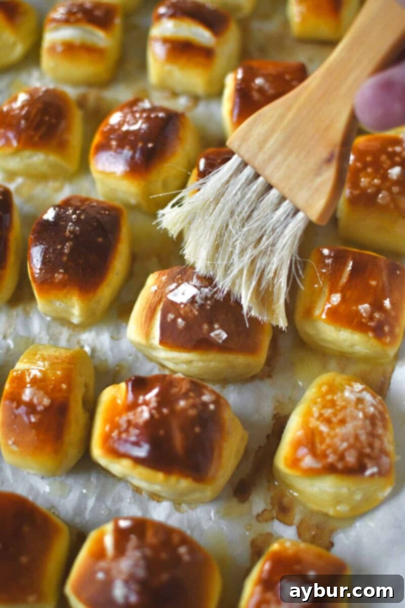Brushing the baked pretzel bites with melted butter after baking.