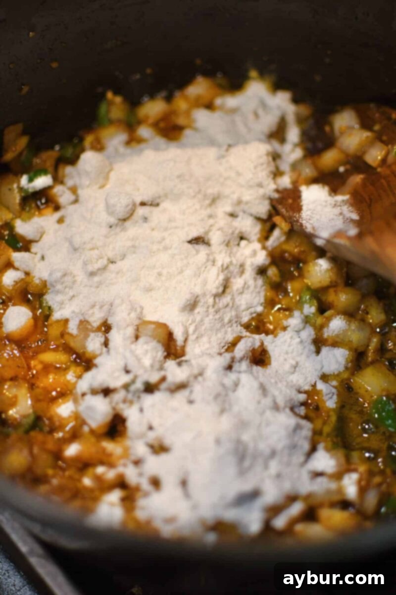 Dusting the soup base with flour to form a roux for thickening.