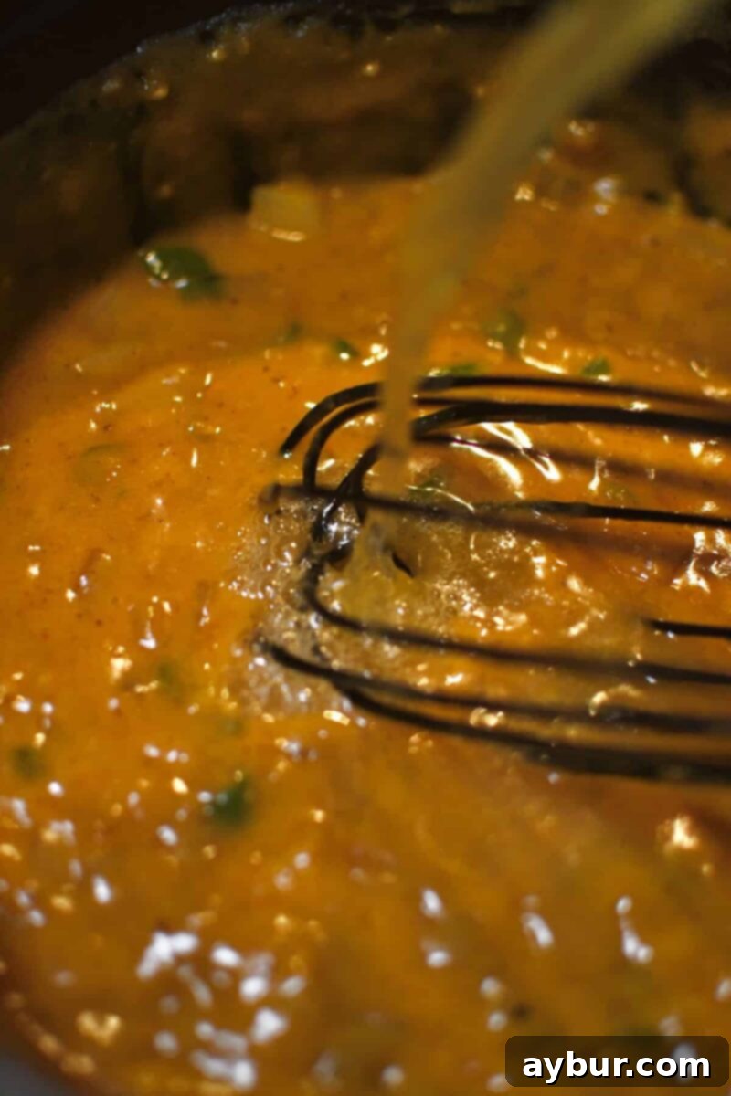 Whisking in the chicken stock to create the soup liquid base.