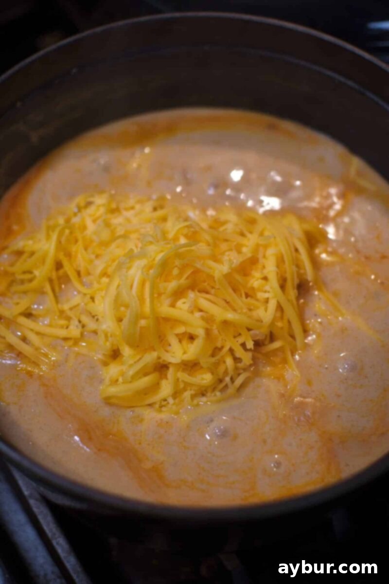 Adding the cheeses to the soup before blending to achieve a smooth consistency.