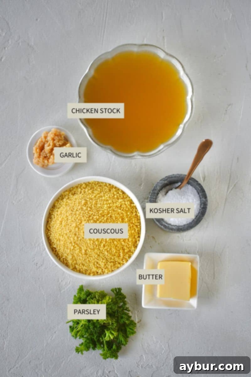 All essential ingredients laid out on a kitchen counter for making flavorful couscous: couscous, chicken stock, butter, garlic, parsley, and salt.