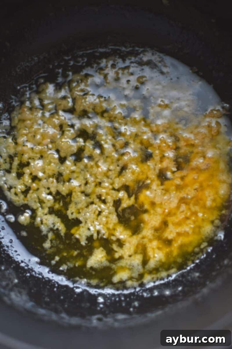 Melted butter gently bubbling with minced garlic in the bottom of a stainless steel saucepan, beginning to brown around the edges.