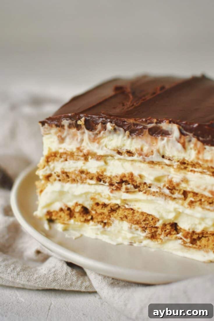A slice of Eclair Cake on a white plate, showcasing its layers, ready to be enjoyed.