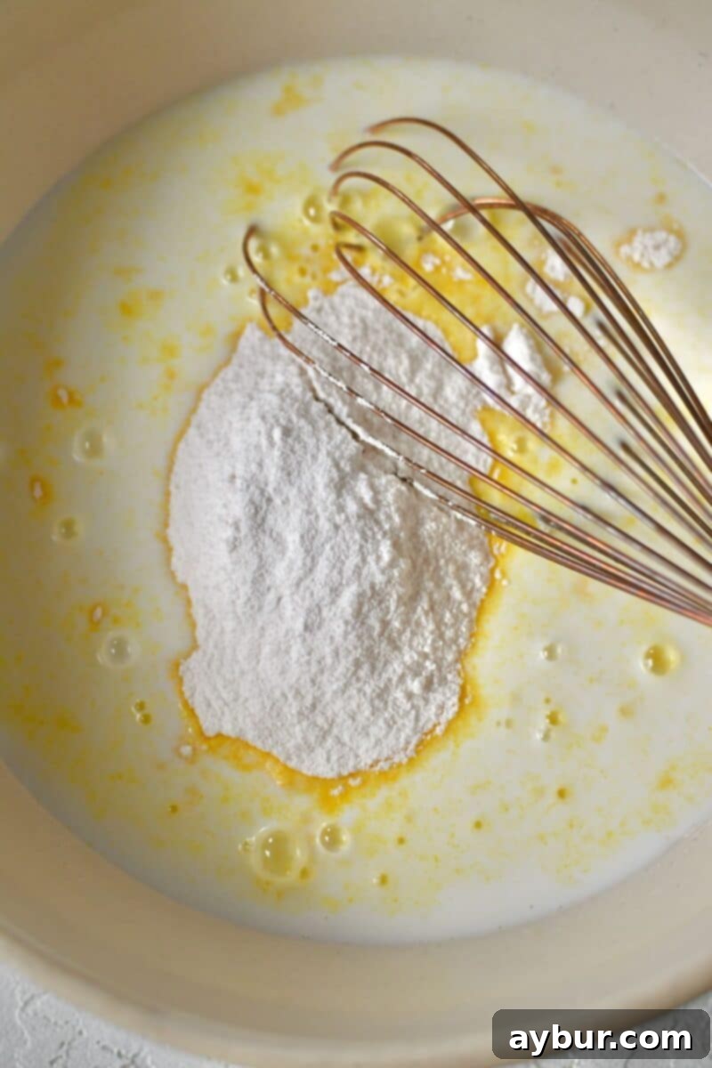 Milk and two packages of instant pudding mix are placed in a bowl, ready to be whisked together into a creamy mixture.