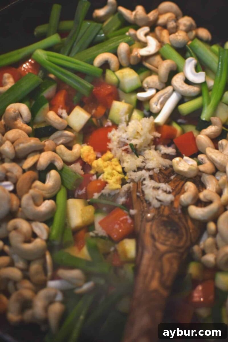 Adding the aromatics and cashews to the pan to toast before adding the chicken and sauce in.