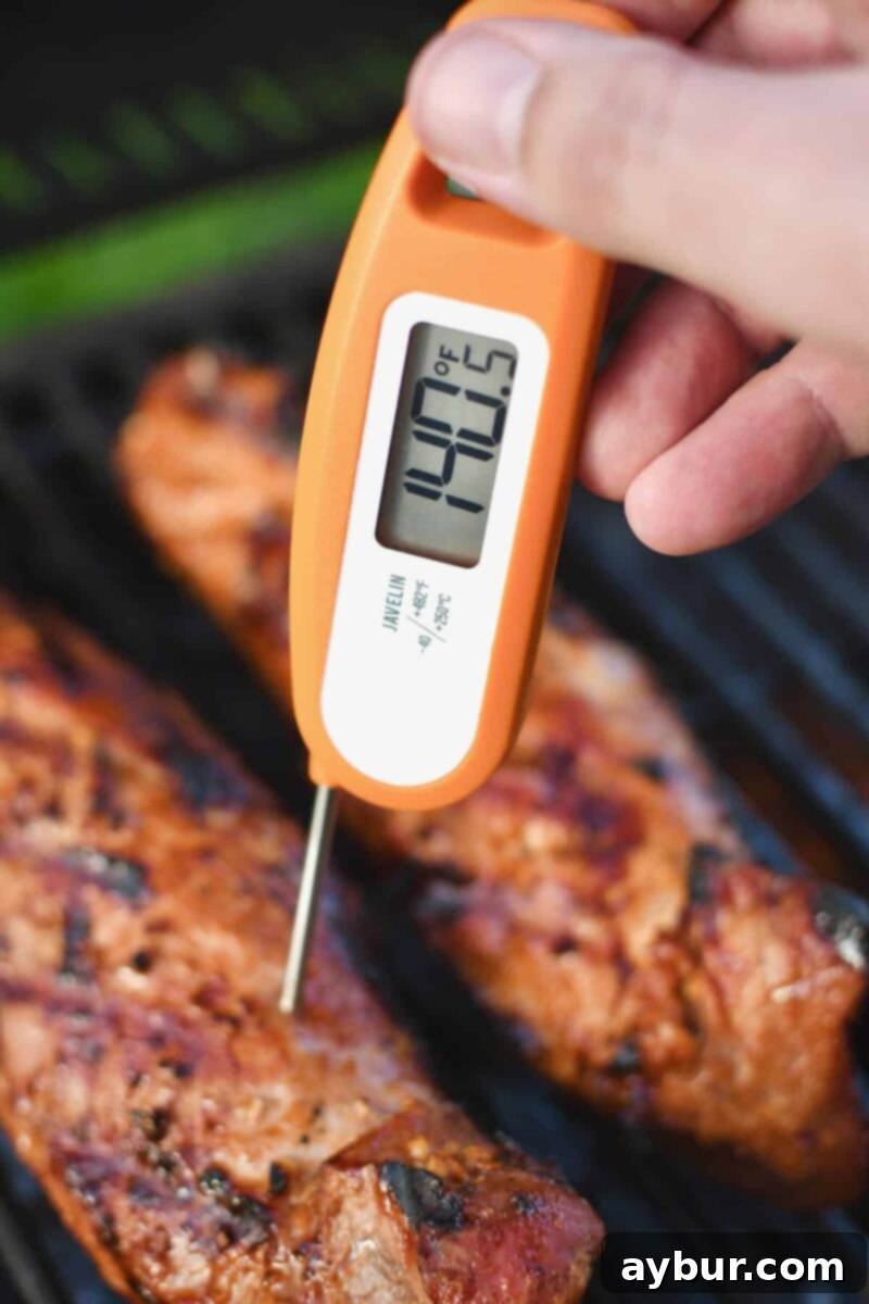 Checking the internal temperature of grilled pork tenderloins, showing a perfect 140˚F reading.