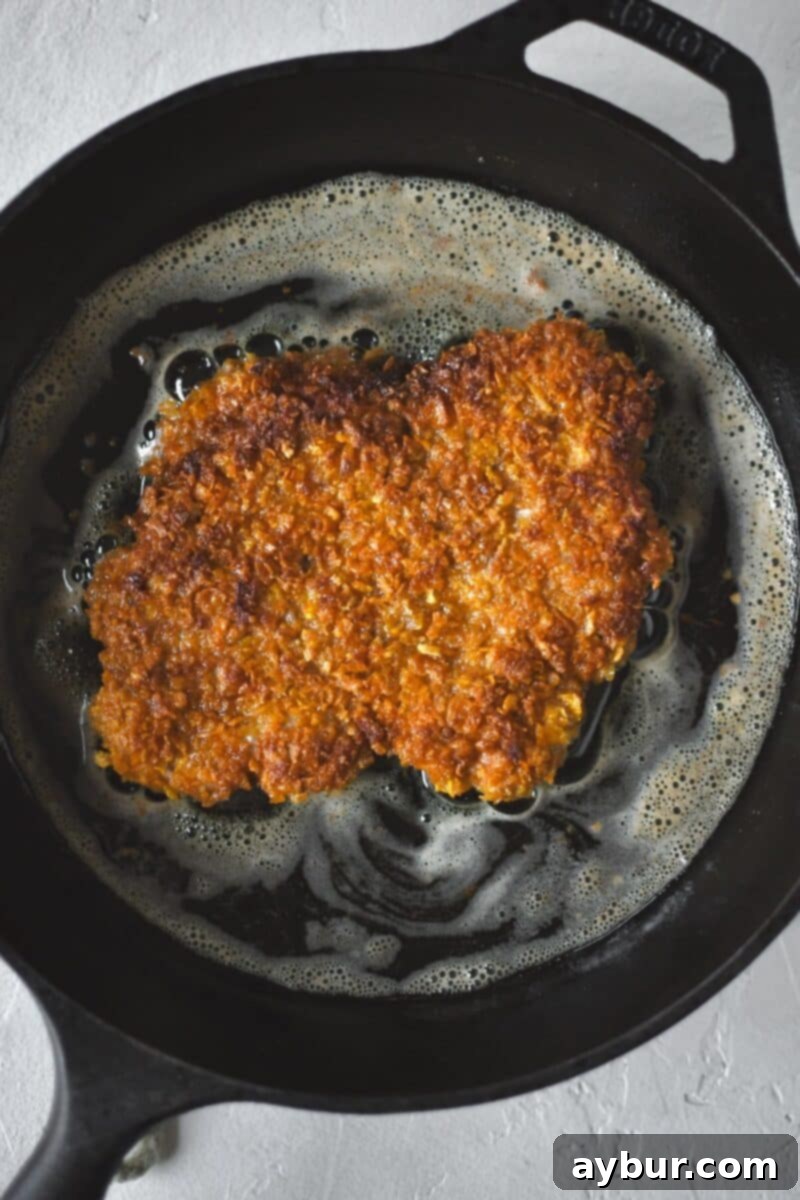 Pan-Fried Pork Perfection 6 A breaded pork cutlet frying in a hot cast-iron skillet, achieving a golden-brown and crispy crust.