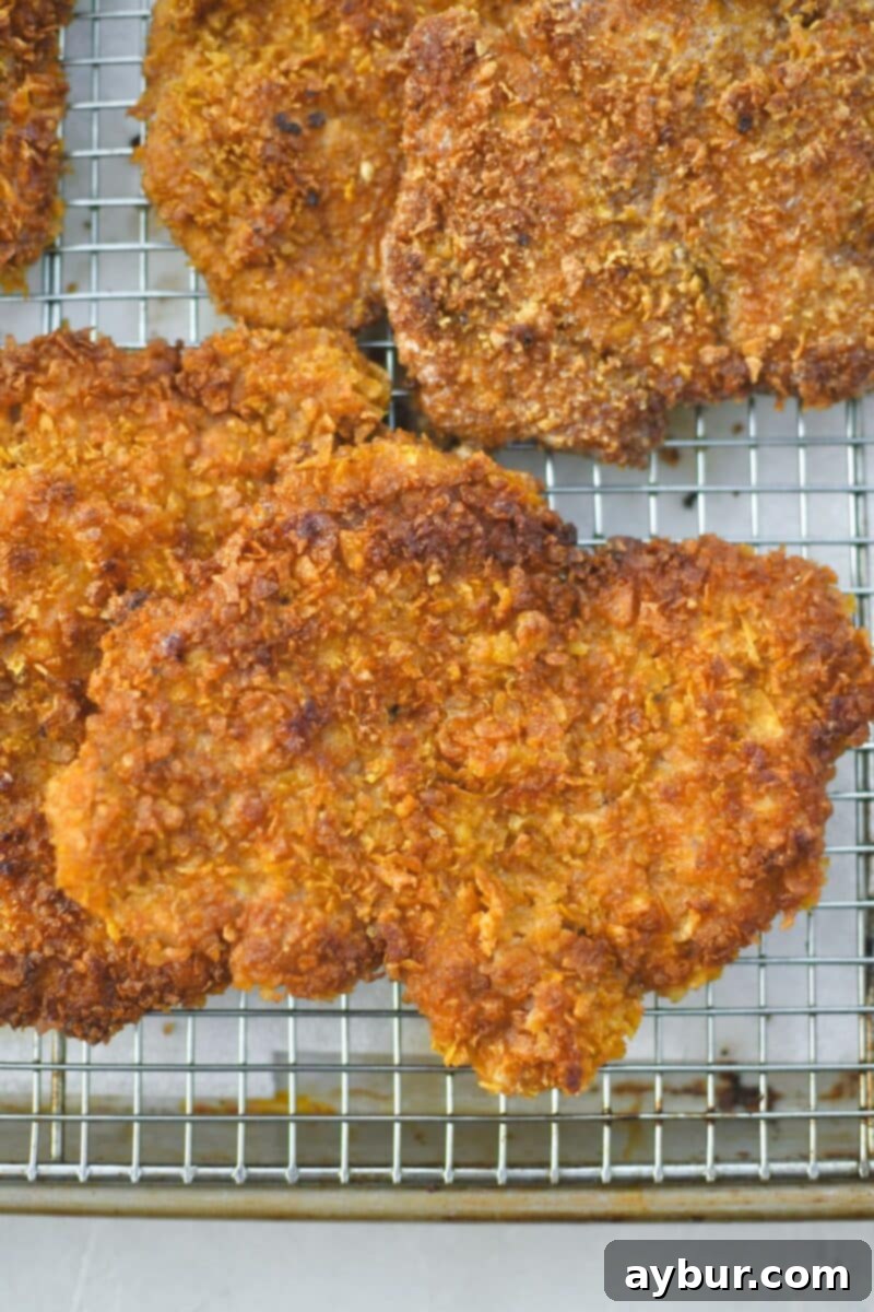 Pan-Fried Pork Perfection 7 Freshly fried schnitzel resting on a wire rack over a paper towel-lined tray to maintain maximum crispiness.