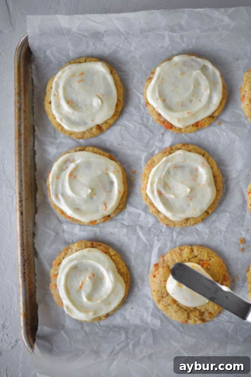 Spiced Carrot Cake Cookies 13 Spreading the frosting over the cookies with a small offset spatula, creating a smooth and appealing finish.