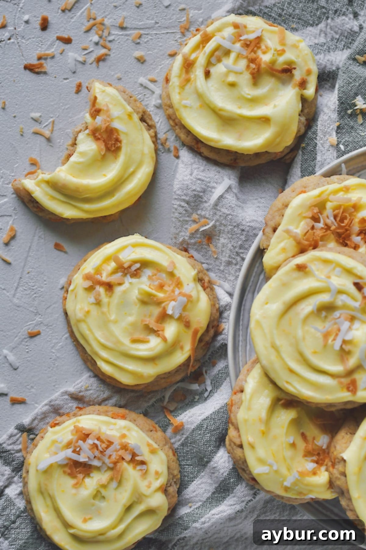 Spiced Carrot Cake Cookies 18 Carrot Cake Cookies laid out on a table. Toasted coconut scattered around and on top of some of the cookies, adding a delightful crunch and tropical flavor.