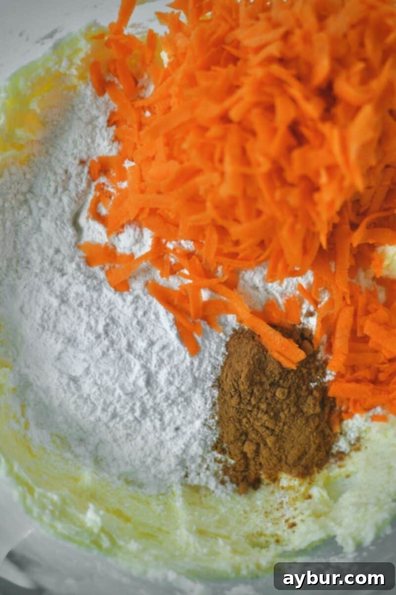 Spiced Carrot Cake Cookies 6 Adding the dry ingredients (flour, salt, baking powder, cinnamon) and shredded carrots to the wet mixture in the stand mixer.