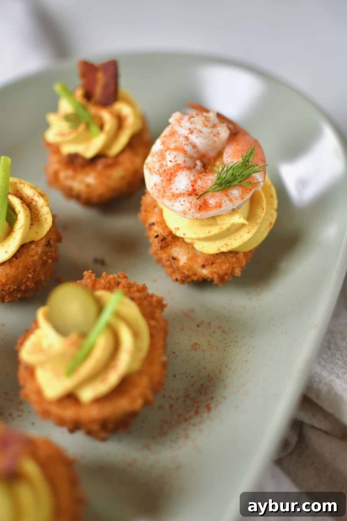 Crispy Deviled Eggs 11 Finished Deep Fried Deviled Eggs on a platter topped with an array of optional toppings like sliced gherkins, herbs, bacon, and shrimp.