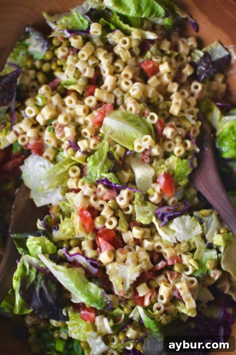 Gently tossing the assembled Italian Pasta Salad to combine all ingredients and dressing.