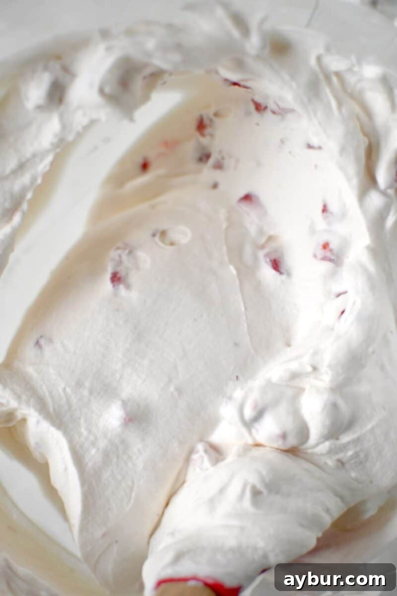Lightly whipped strawberry cream in a stand mixer bowl, ready to be spread.