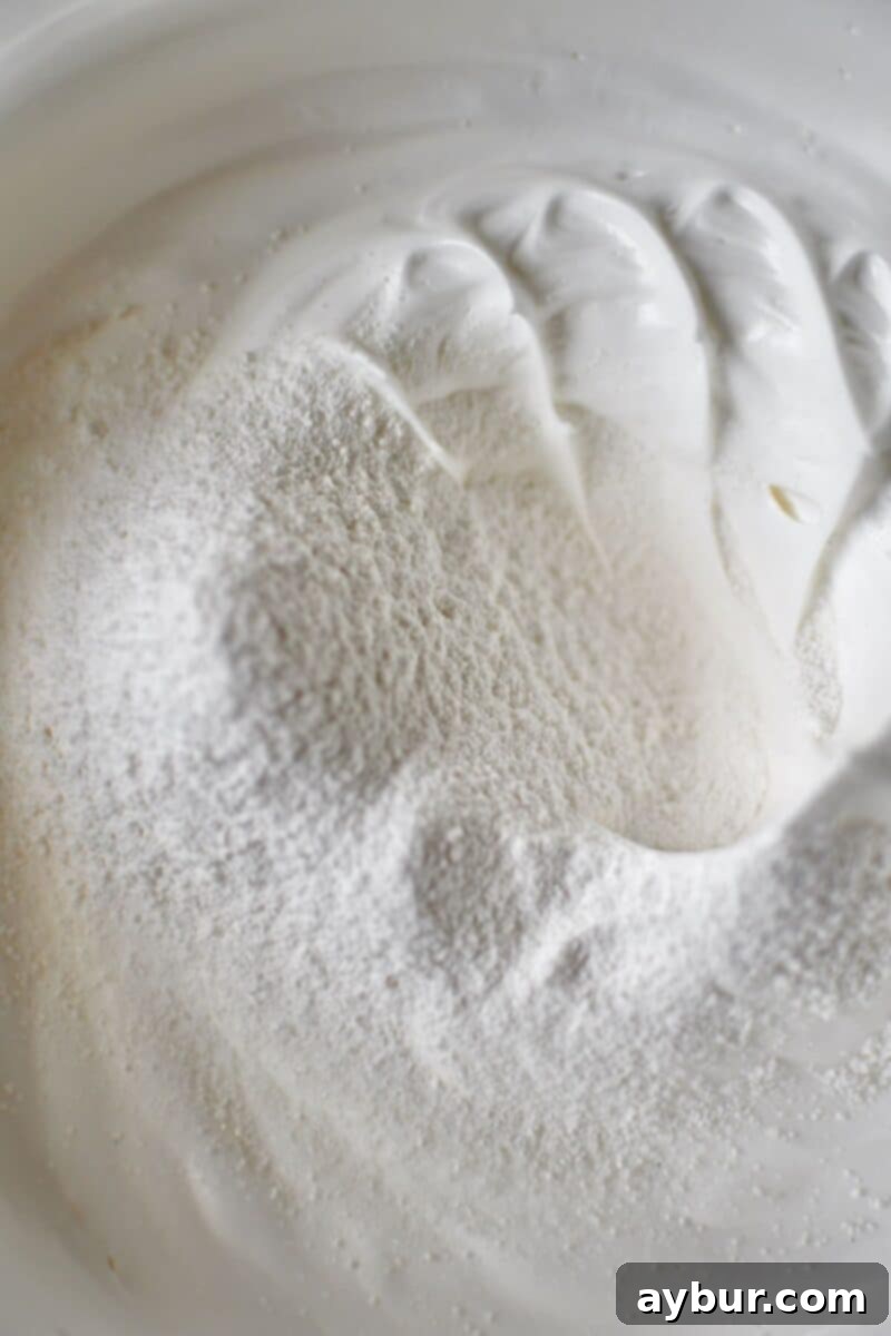 The process of gently folding sifted dry ingredients into the whipped egg whites.