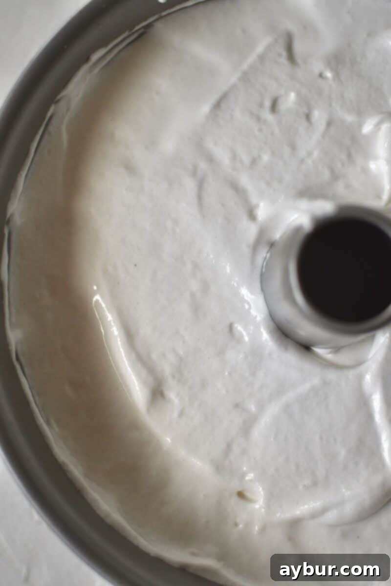 Smooth angel food cake batter evenly distributed in an ungreased tube pan.