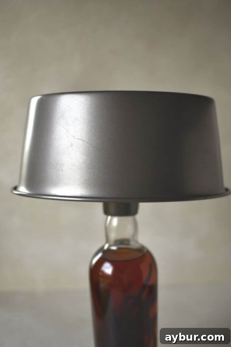 An angel food cake cooling upside down on a wine bottle, a common method for preventing collapse.