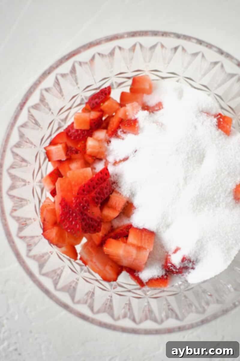 Diced strawberries and sugar placed in a bowl, ready to be mixed.
