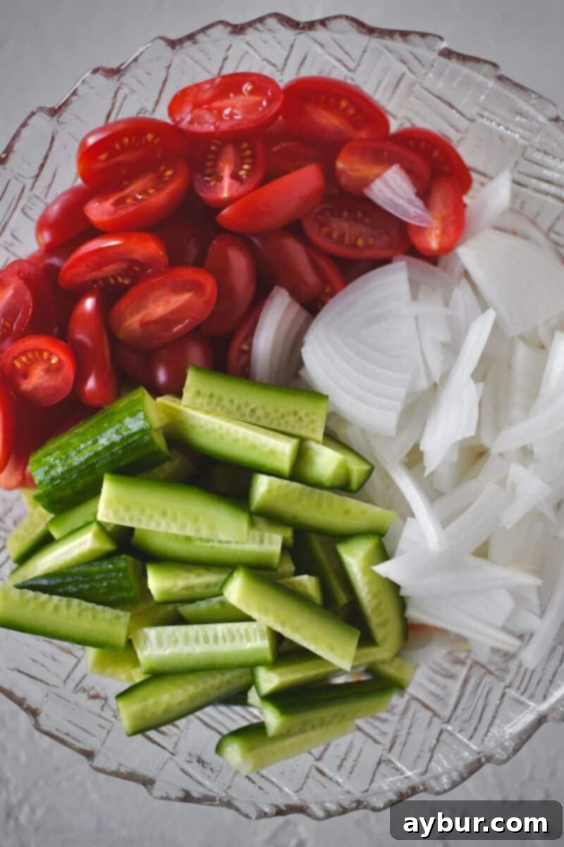 Fresh Garden Medley 6 Freshly chopped cucumbers, tomatoes, and thinly sliced onions placed in a mixing bowl, ready to be tossed with the prepared Chamoy and Tajin marinade.