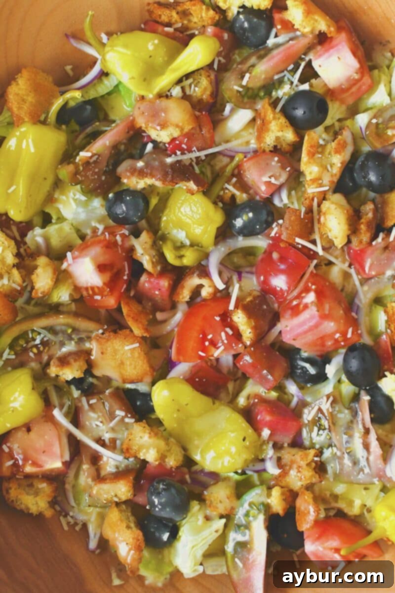 Carefully placing a variety of fresh vegetables on top of the chopped lettuce in a large mixing bowl.