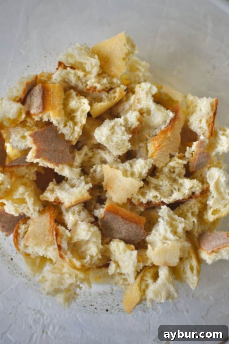 Adding the torn bread into the bowl with the melted butter and spices.