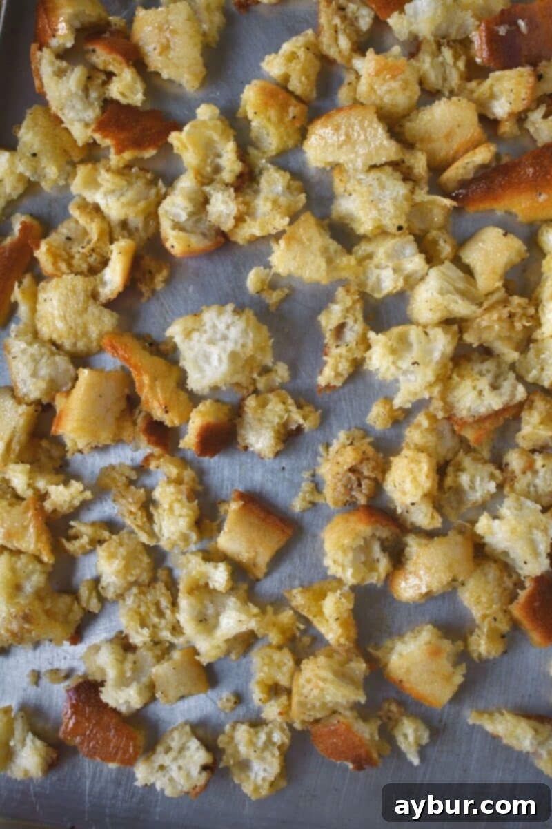 The torn bread that has been tossed in the seasoned butter laid out in a single layer on a baking sheet.