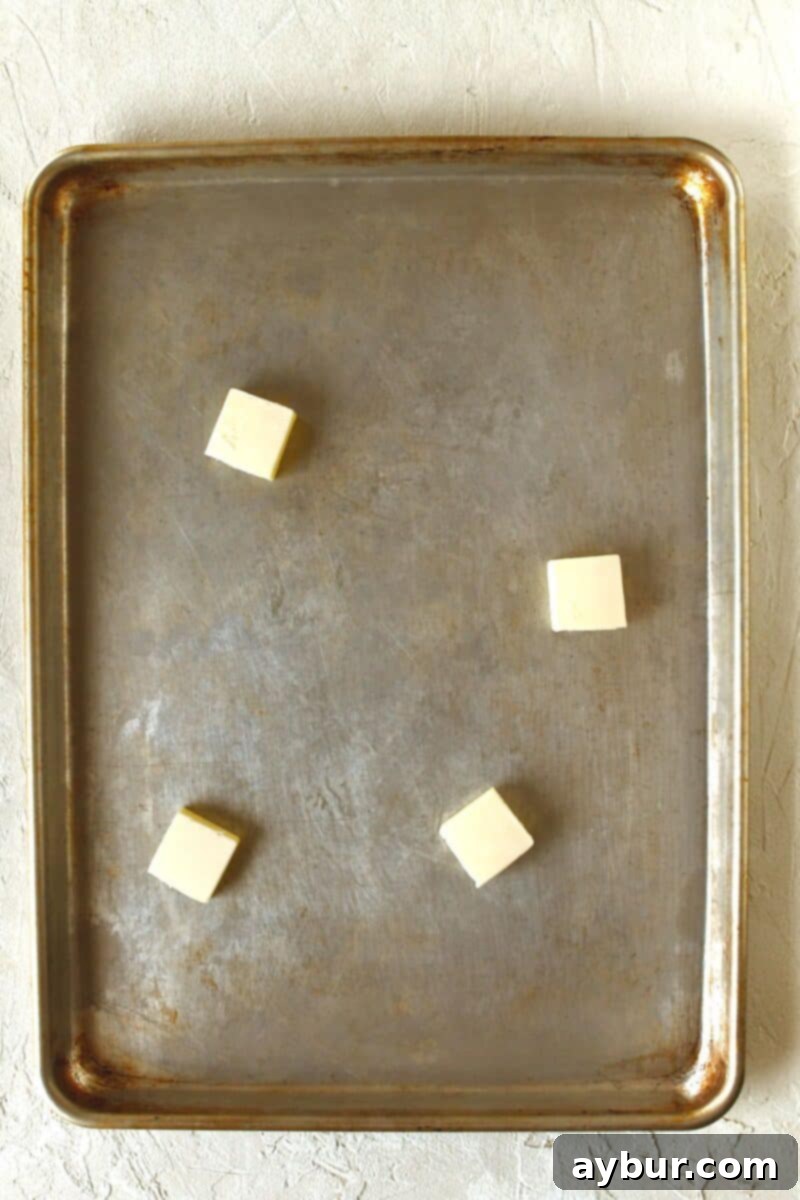 Solid butter placed on a rimmed baking sheet before melting.