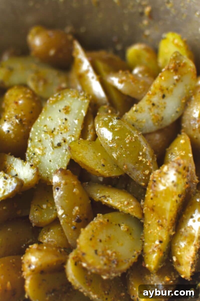 Seasoning halved potatoes with oil, salt, and garlic herb seasoning.