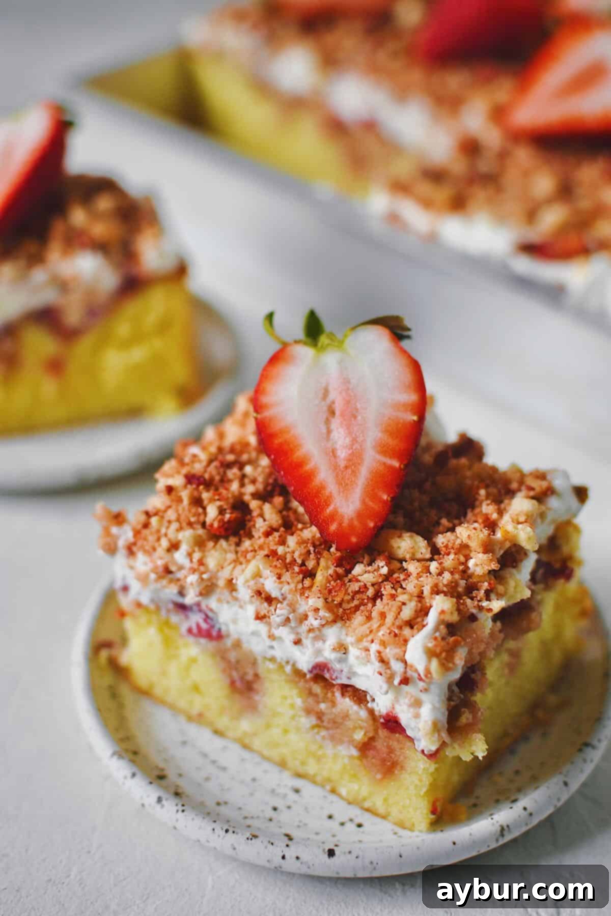 A couple slices of Strawberry Crunch Cake removed from the pan with a fresh strawberry half on top.