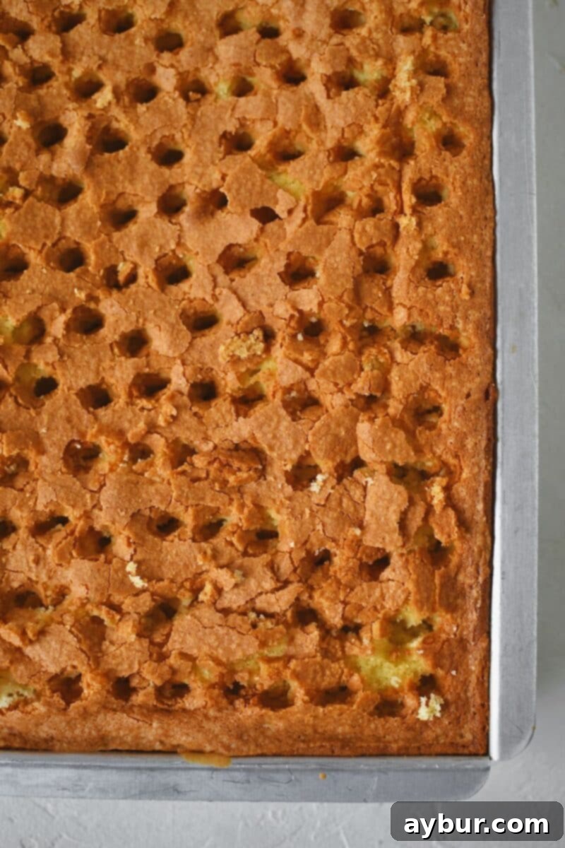 Freshly baked cake just out of the oven, poked with the back of a wooden spoon to create holes.