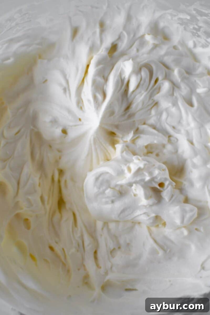 Freshly whipped cream in a stand mixer bowl.