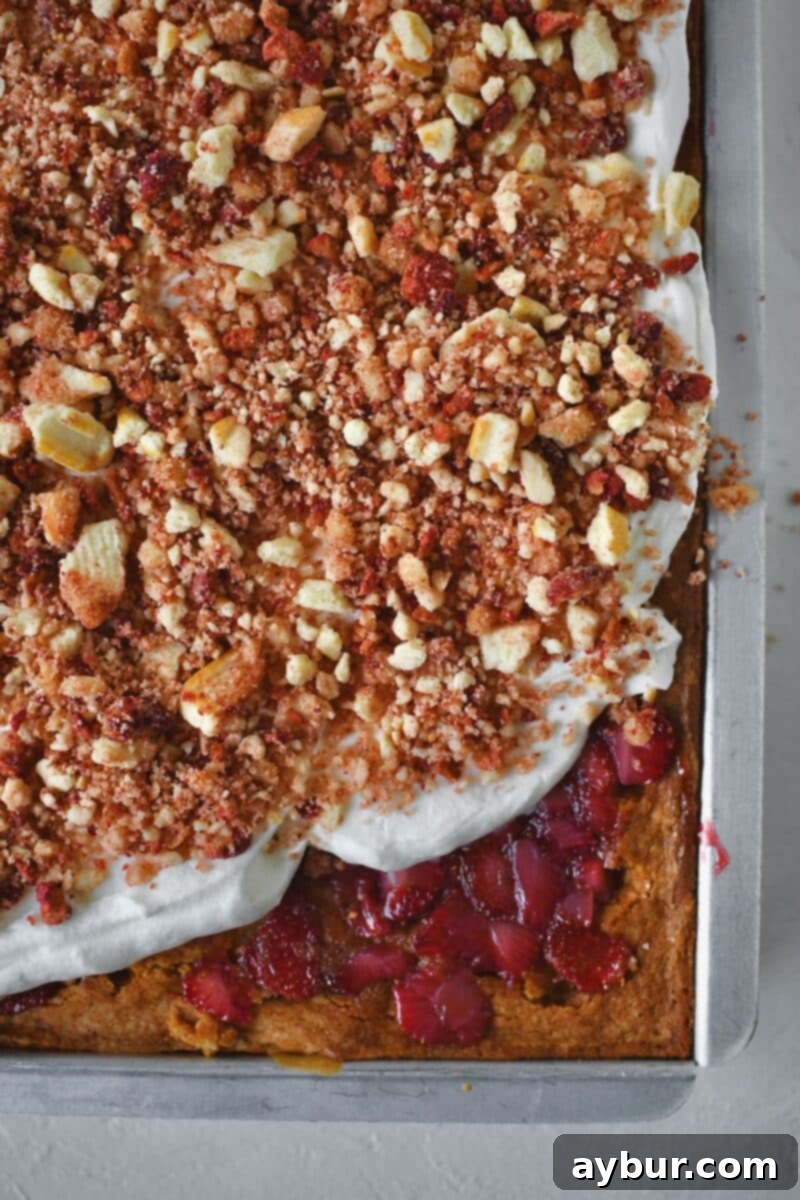 Topping the cake with whipped cream and crushed strawberry cookie topping.