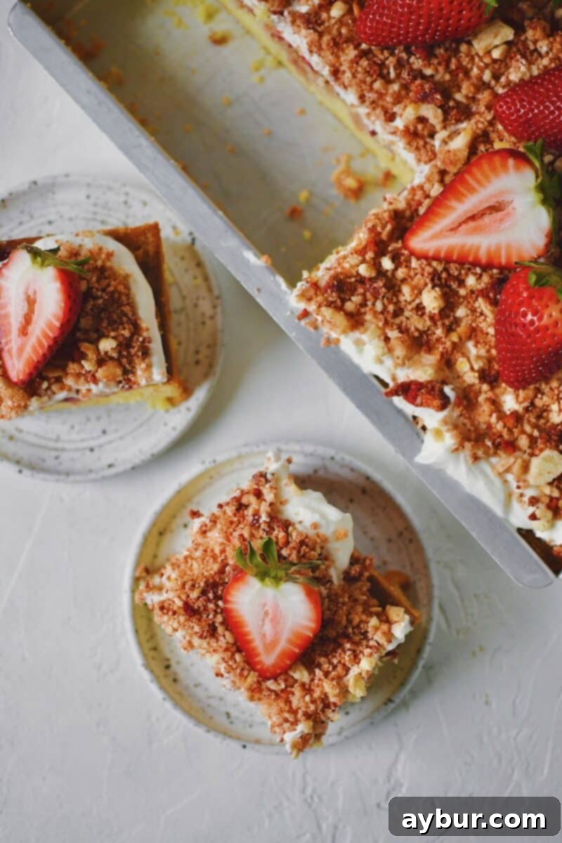 A couple slices of Strawberry Crunch Cake removed from the pan with a fresh strawberry on top.