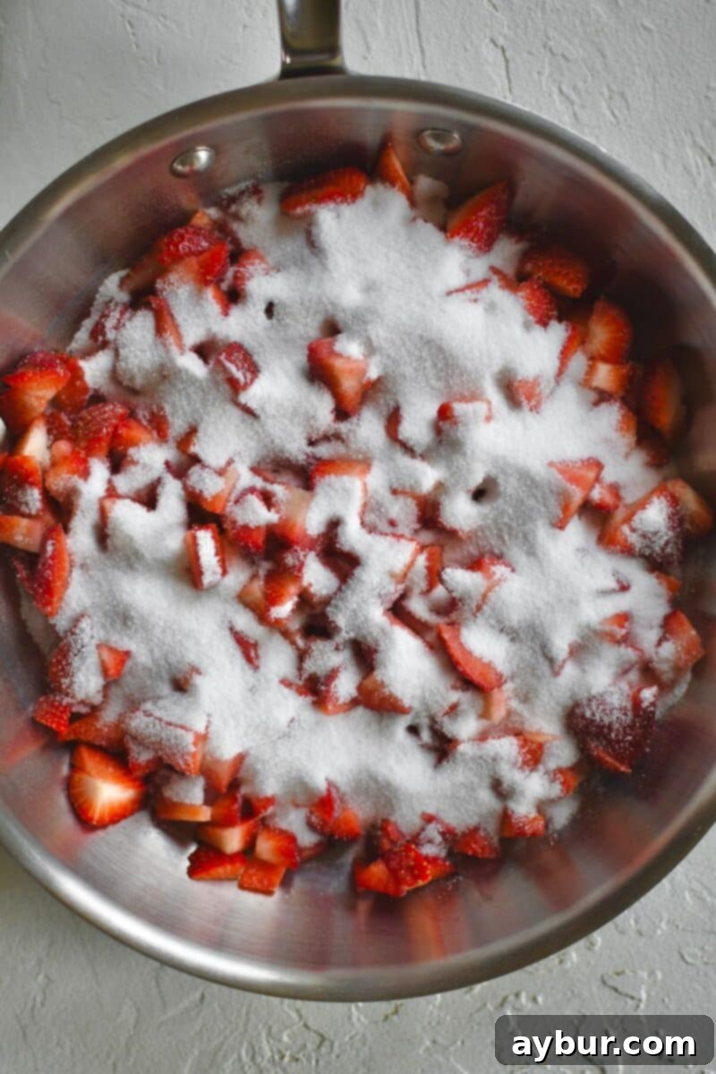 Diced strawberries and sugar in a saute pan before cooking.